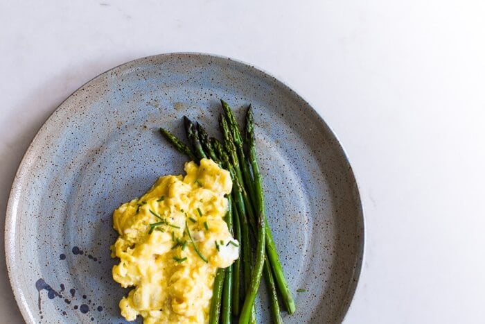 Fluffy scrambled eggs on a plate with asparagus