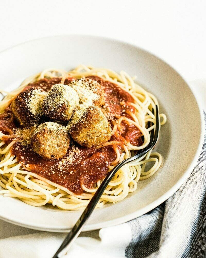 Vegan parmesan cheese on vegan meatballs with spaghetti