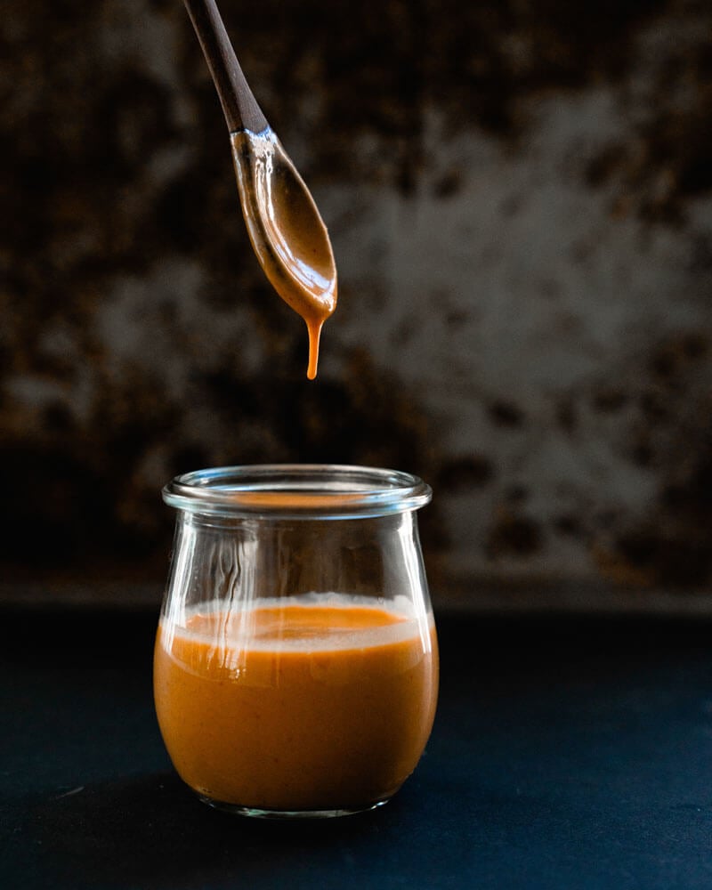 spoon hovering above glass filled with chipotle sauce