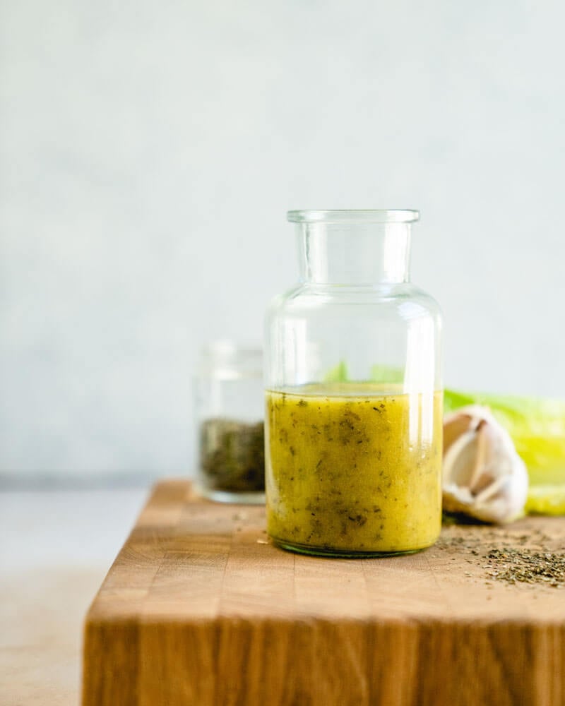 Homemade Italian dressing recipe in glass jar with garlic and herbs
