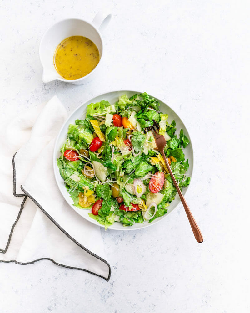 Chopped salad in white bowl with napkin and Italian dressing