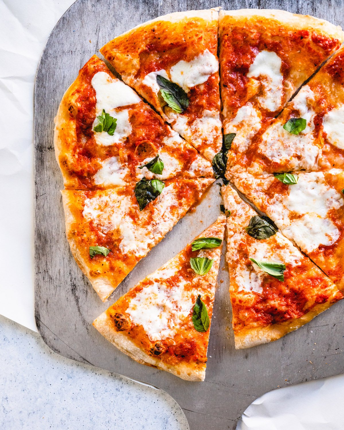 Neapolitan pizza on pizza peel with basil and fresh mozzarella.