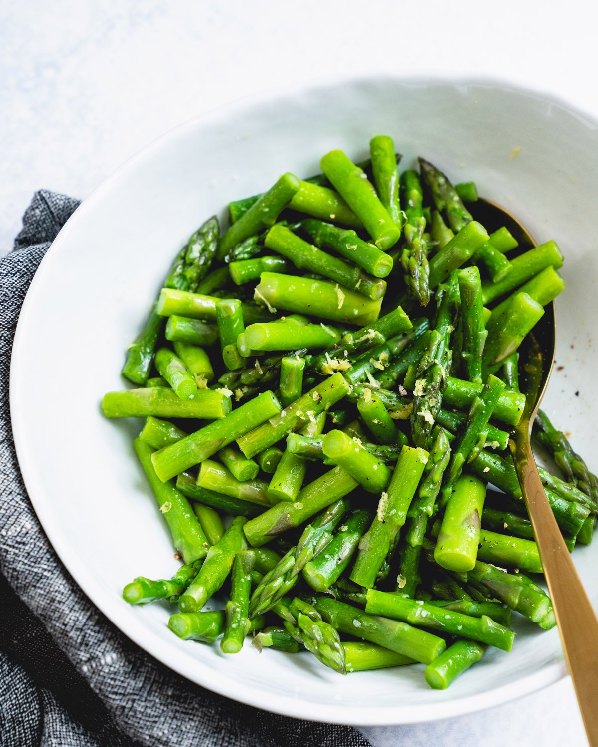 Steamed Asparagus in bowl with spoon.