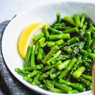 Steamed asparagus in bowl with lemon.