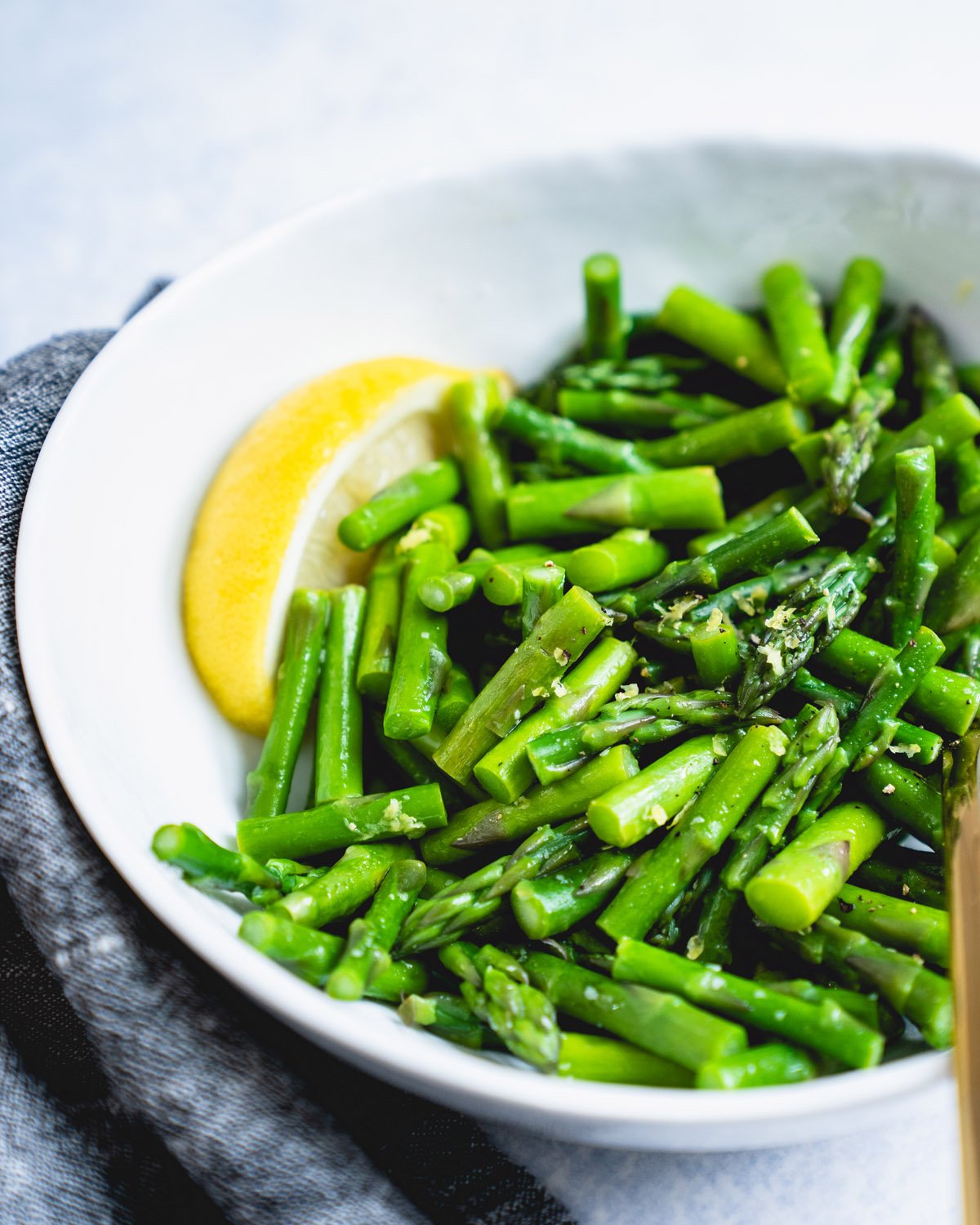 Steamed asparagus in bowl with lemon.