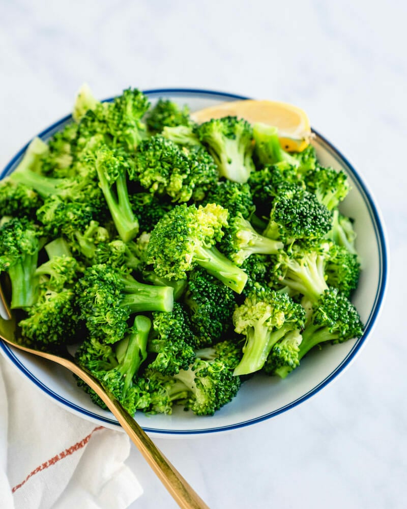 Boiled broccoli in bowl with lemon wedge