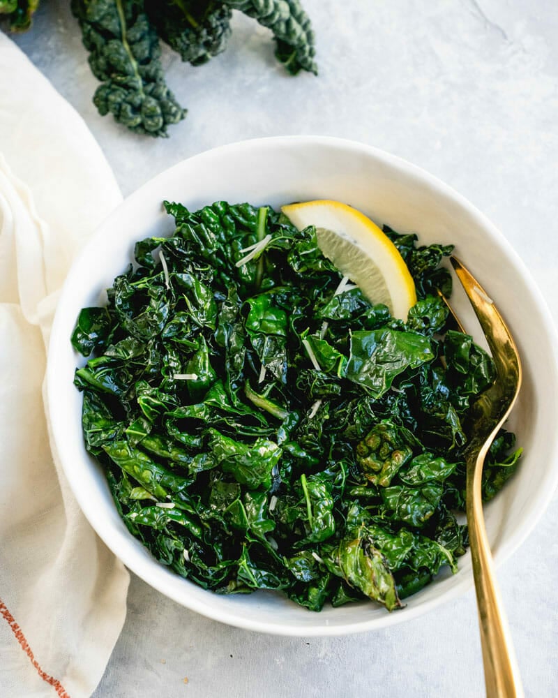 Sauteed kale in bowl with lemon and fork