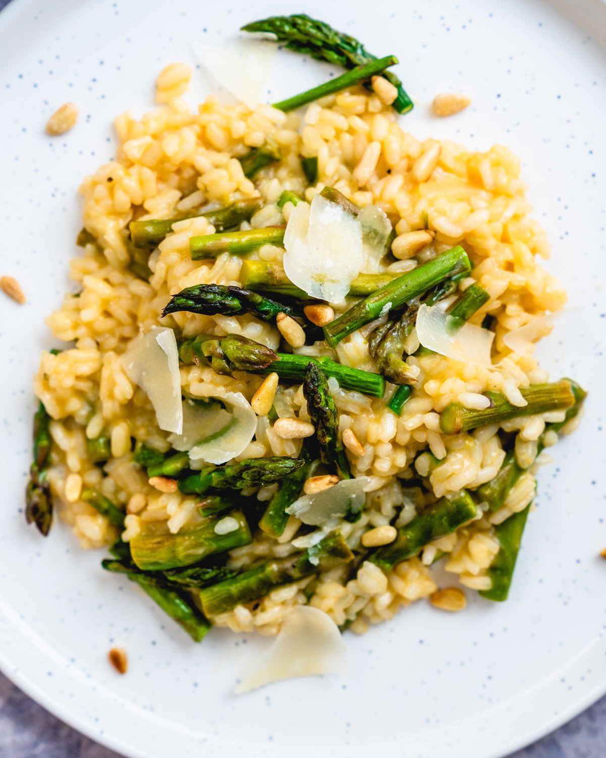 Asparagus risotto garnished with Parmesan cheese shavings and pinenuts.