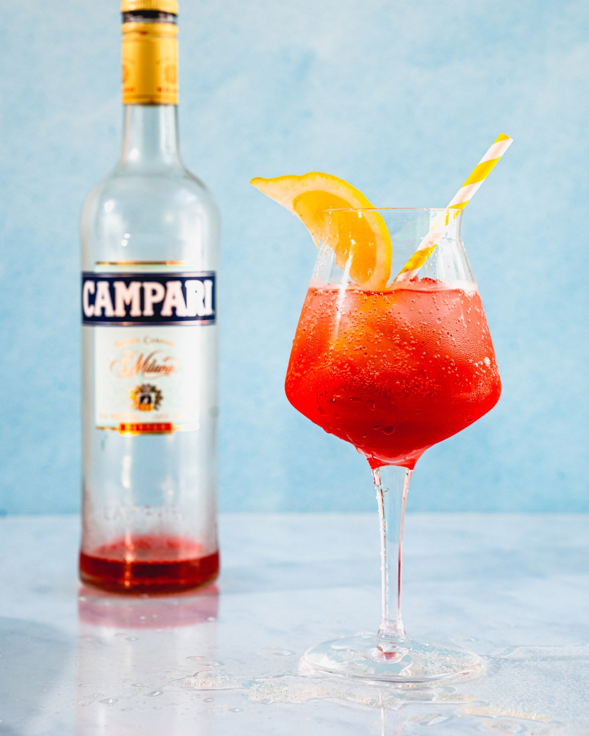 Campari Spritz in glass with campari bottle.