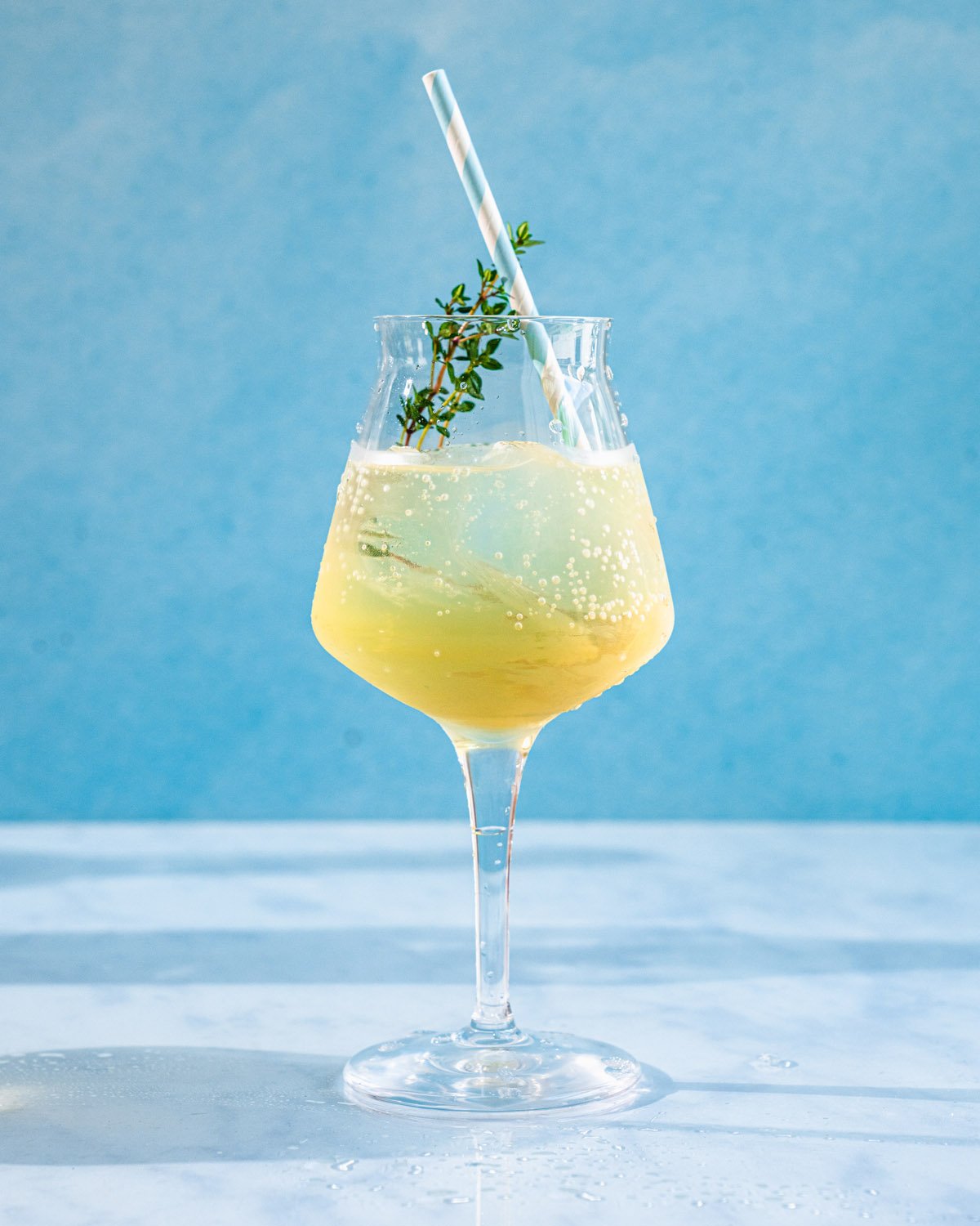 St germain spritz in stemmed cocktail glass with thyme garnish.