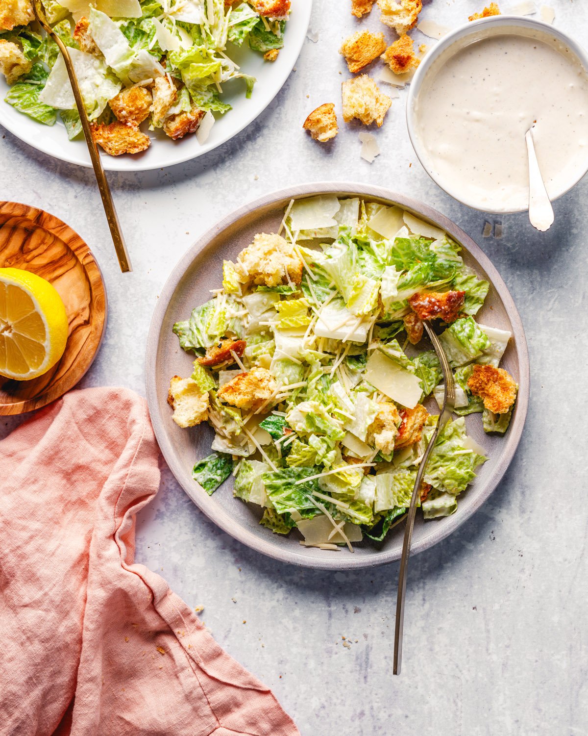 Caesar Salad recipe on plates with Caesar dressing and lemon. 