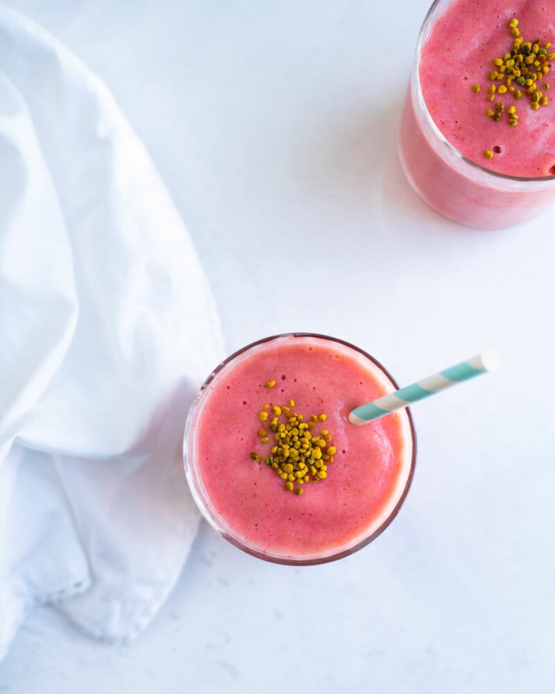 Almond milk smoothie with strawberries and banana in glass with straw