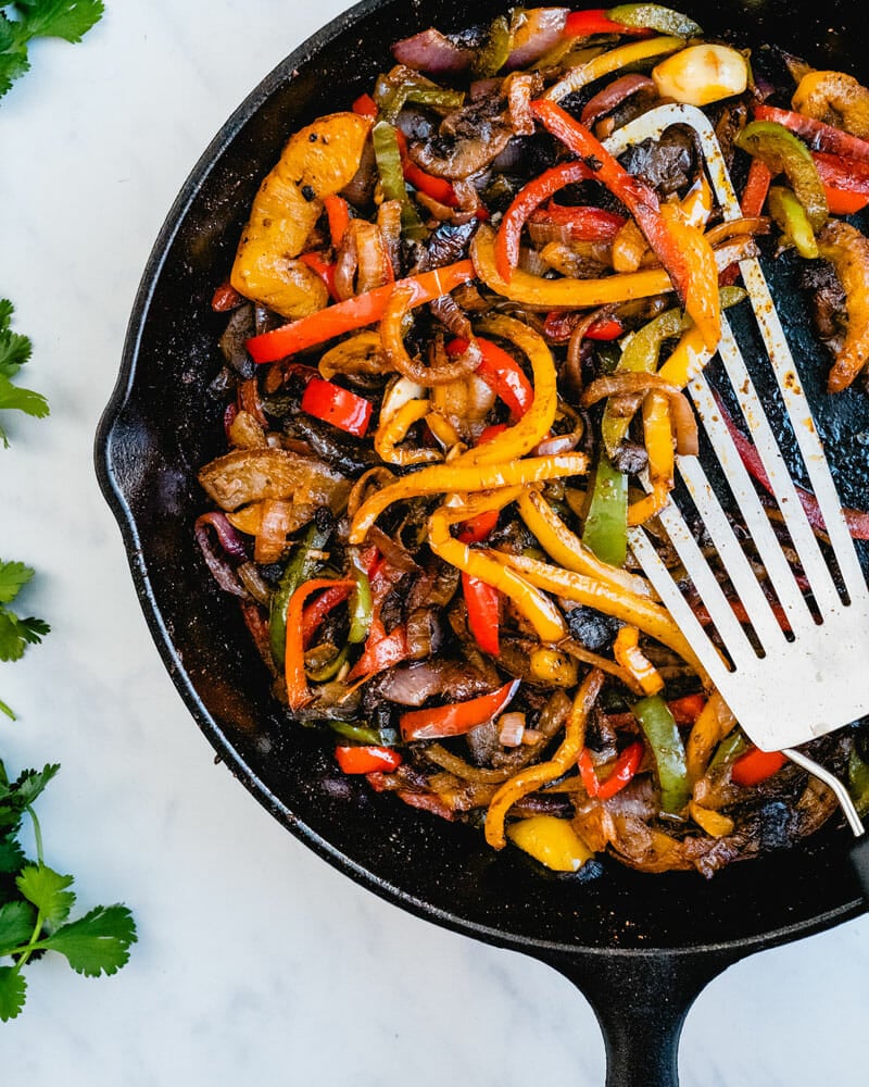 Fajita veggies being cooked in a skillet
