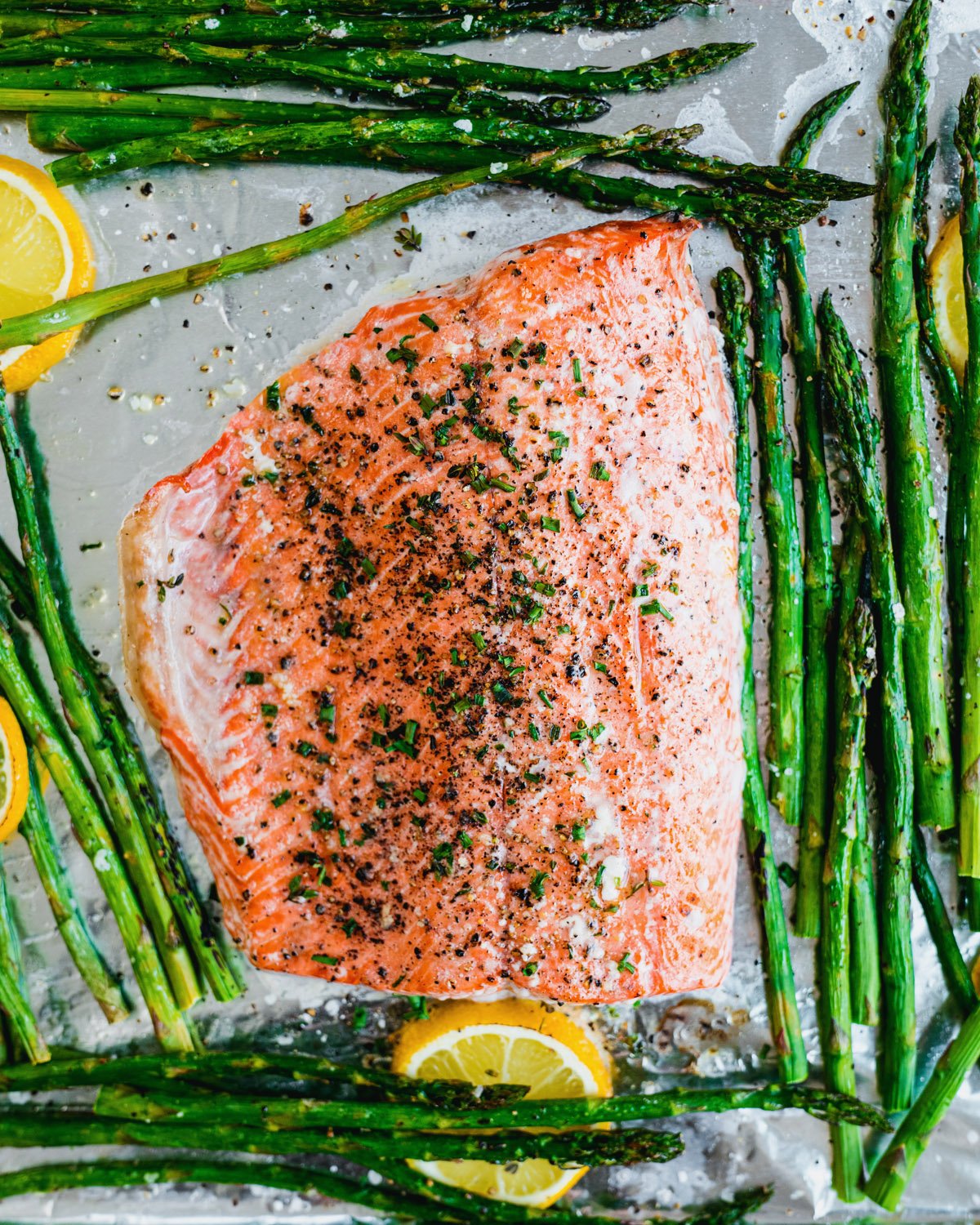 Salmon and asparagus on sheet pan with lemon slices.