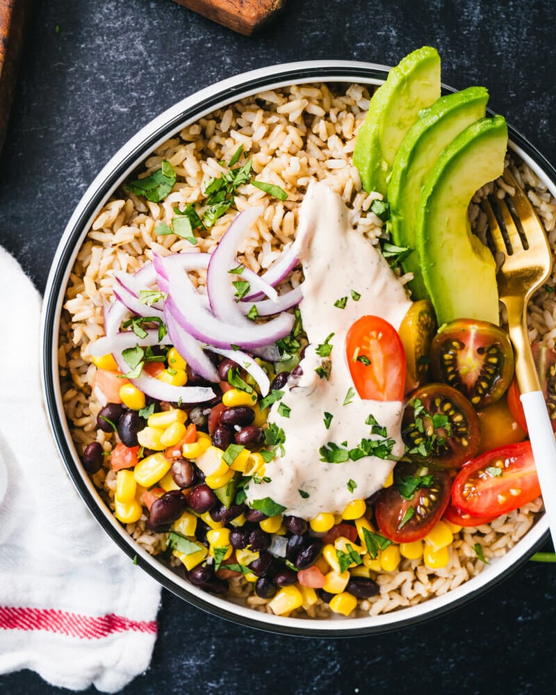 Burrito bowl with black bean and corn salad, avocado, red onion, tomatoes and rice.