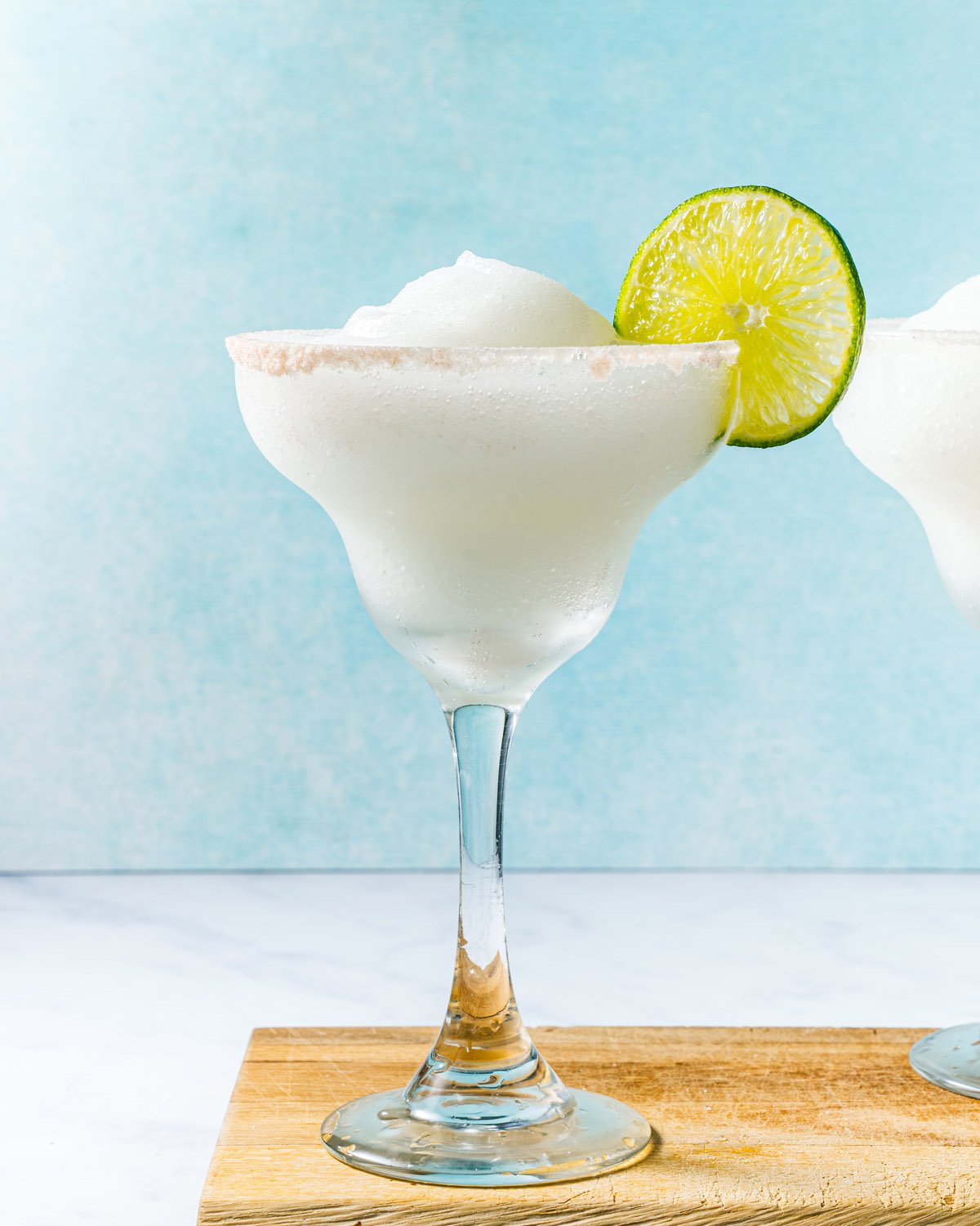 Frozen margarita in glass with salt rim and lime wheel.