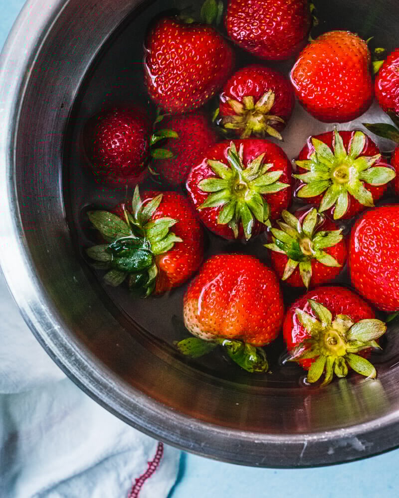 Step 1: Prepare the fresh ingredients: wash and clean the strawberries, salad greens, and slice the onion.