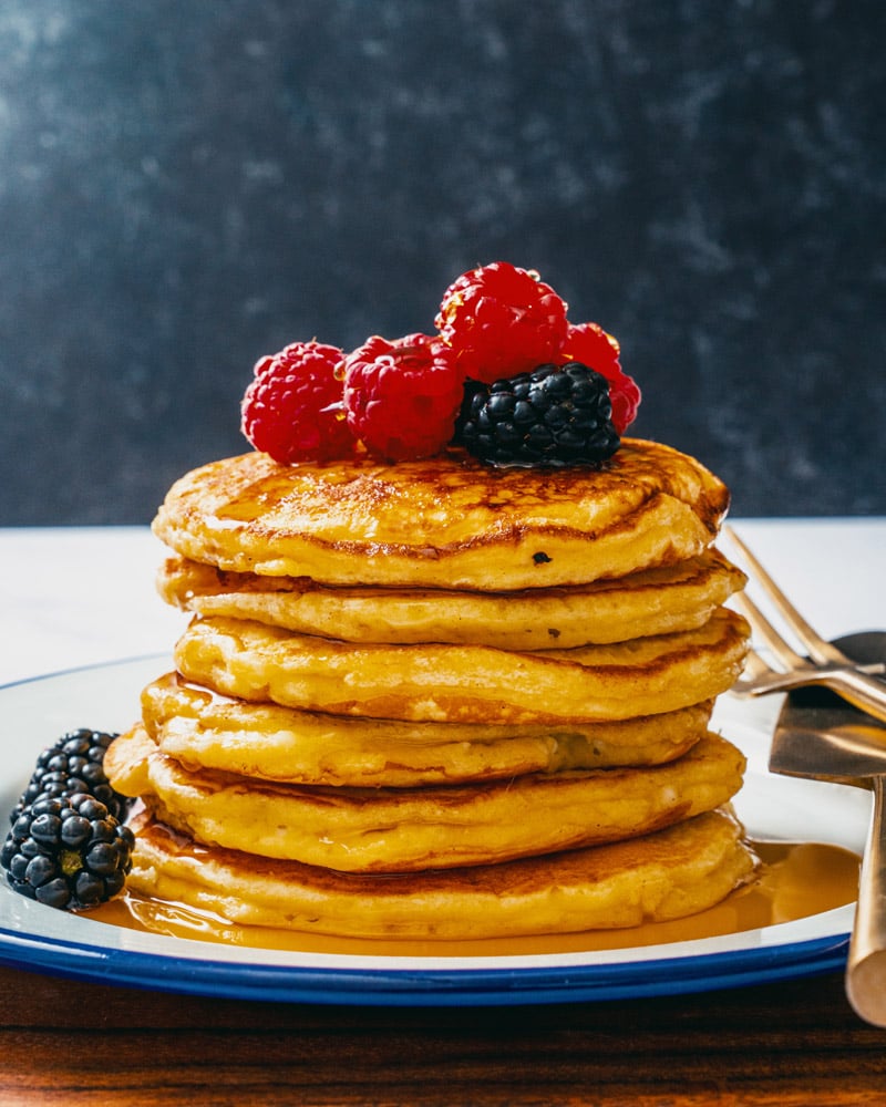 Cottage Cheese Pancakes in a stack with berries and maple syrup.