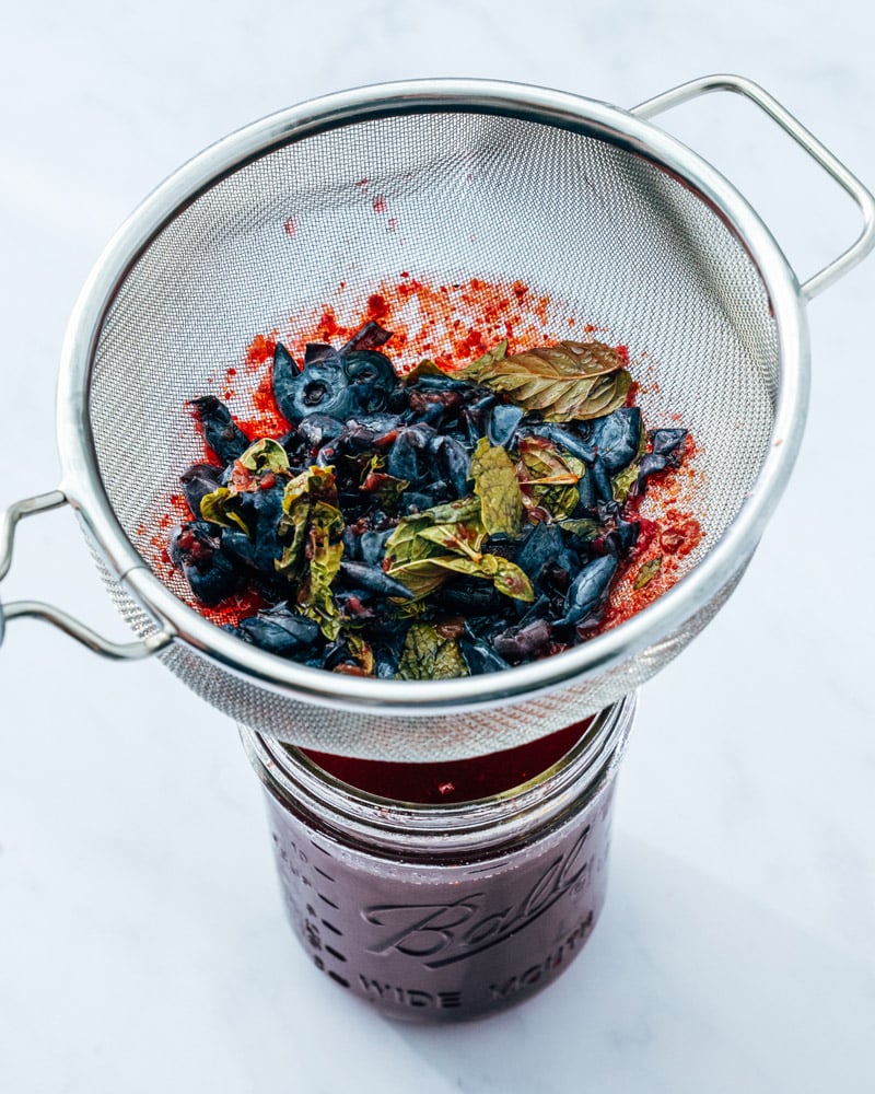 Shrub drink: straining fruit and herbs