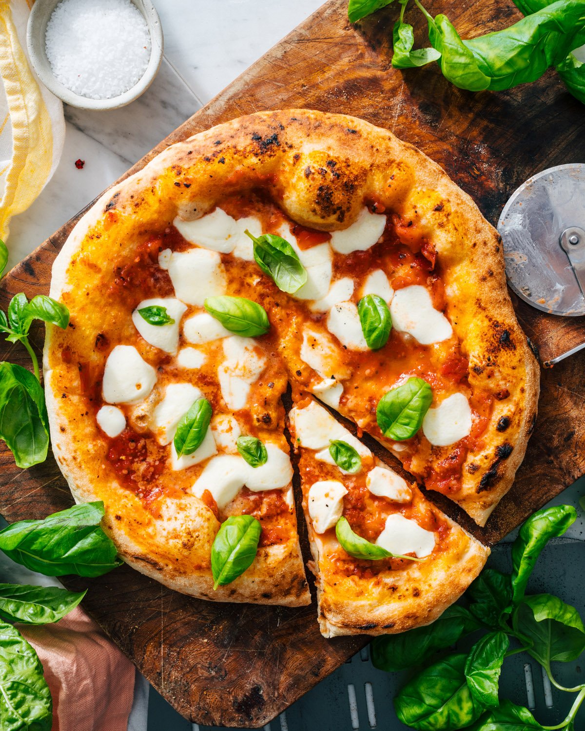 Margherita pizza with pizza sauce and pizza cutter.