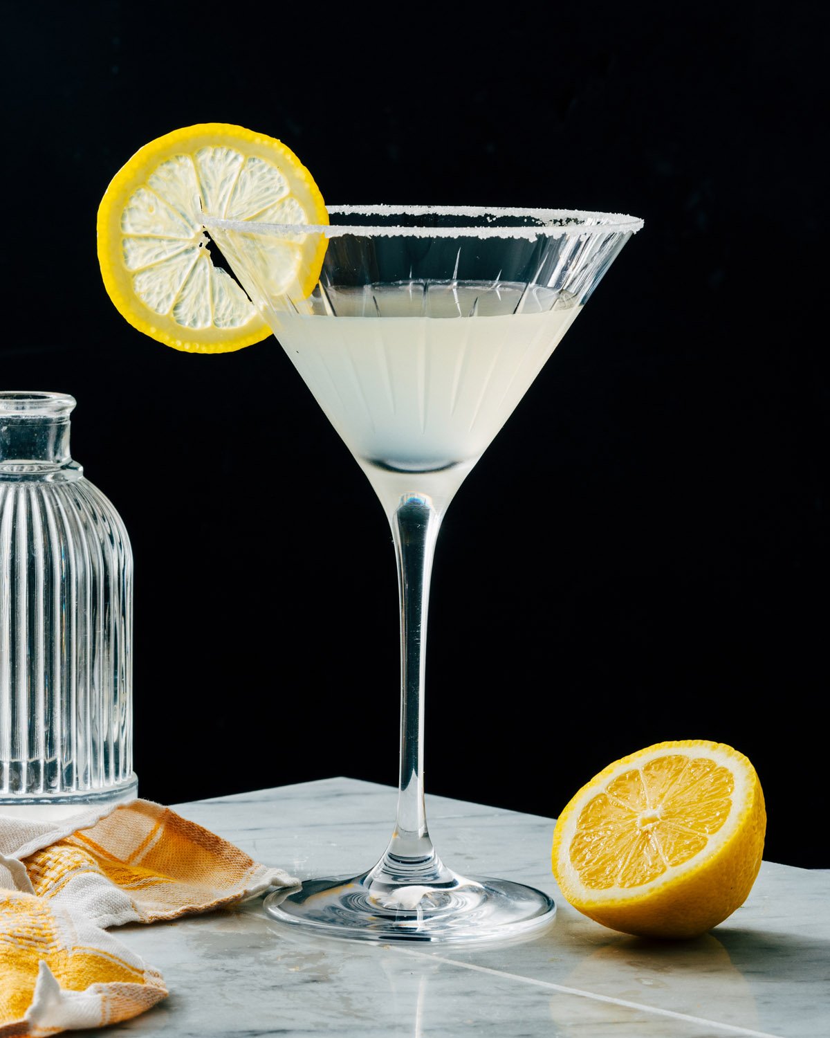 Lemon drop martini in martini glass with lemon garnish and sugar rim.