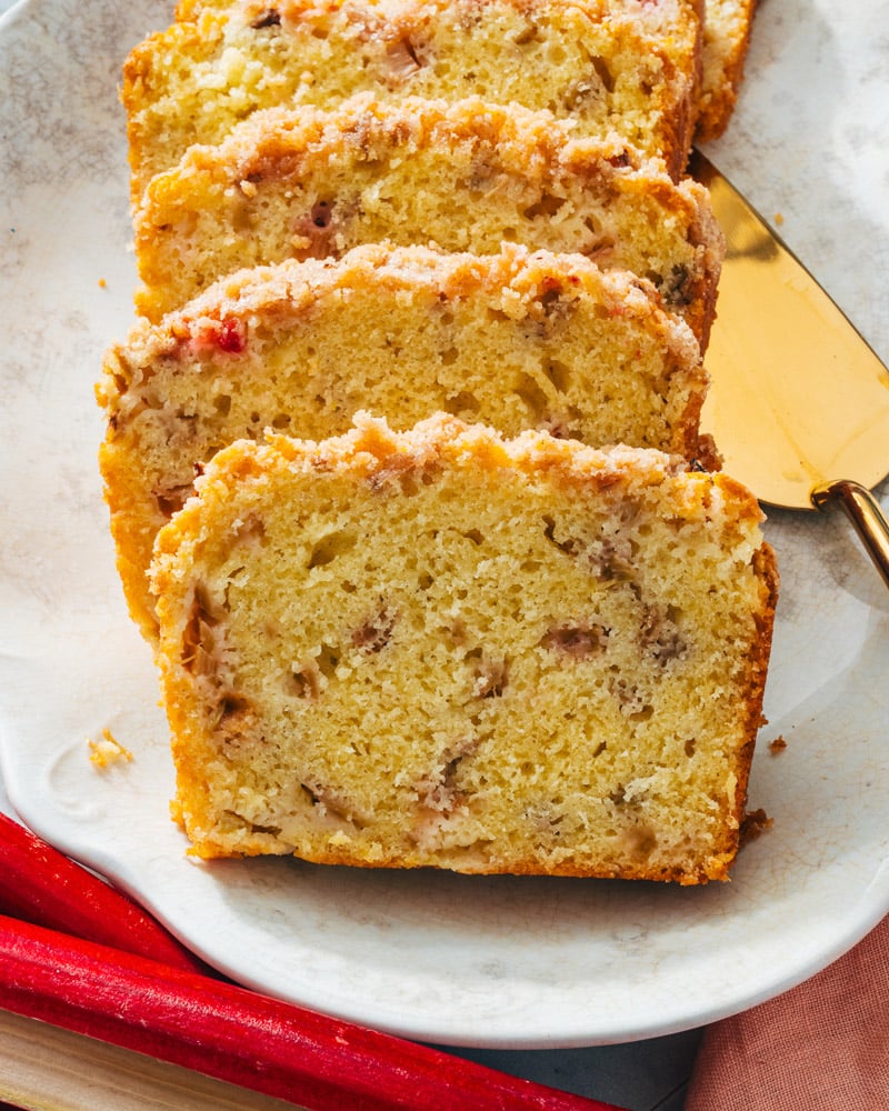 Rhubarb bread on platter with rhubarb stalks.