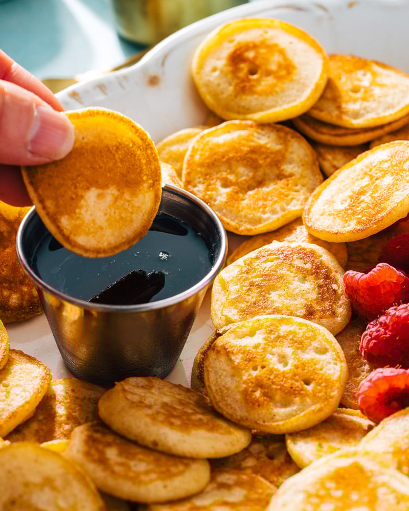 Mini pancakes dunking into syrup
