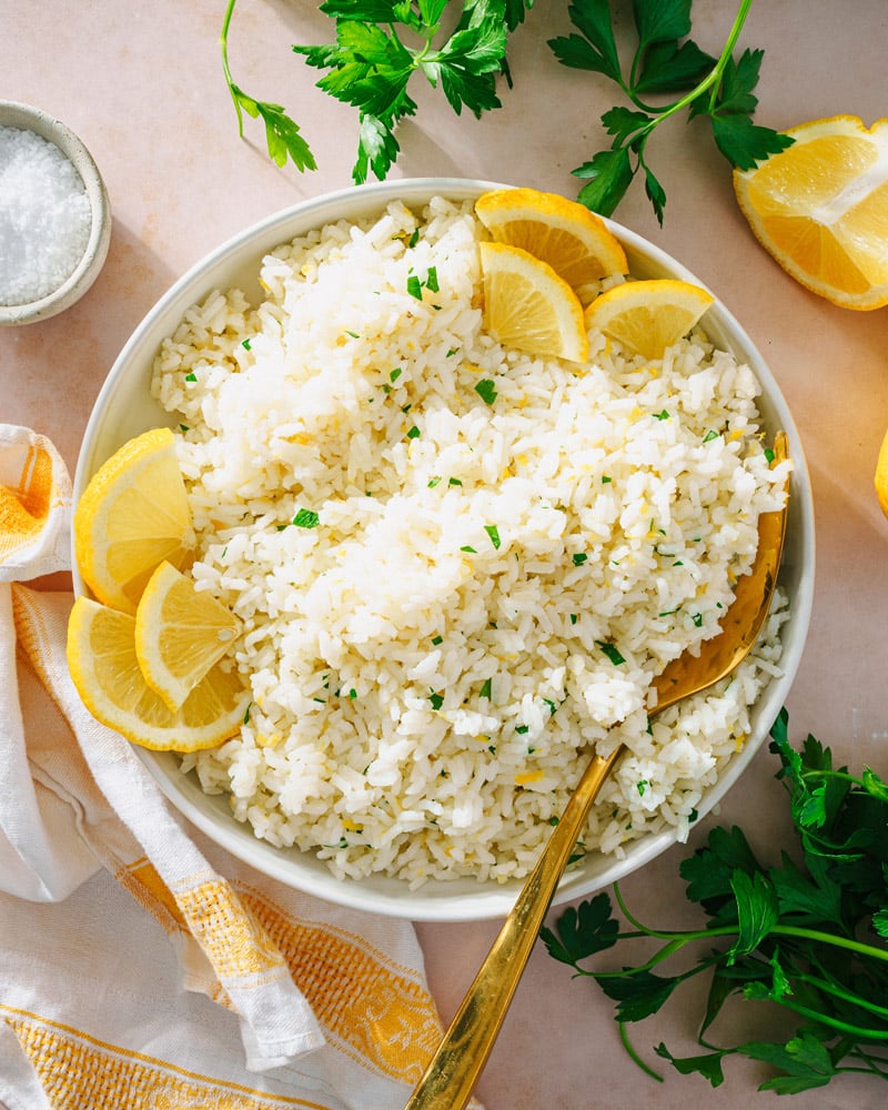 Lemon Rice recipe in bowl with serving spoon, lemons and parsley.