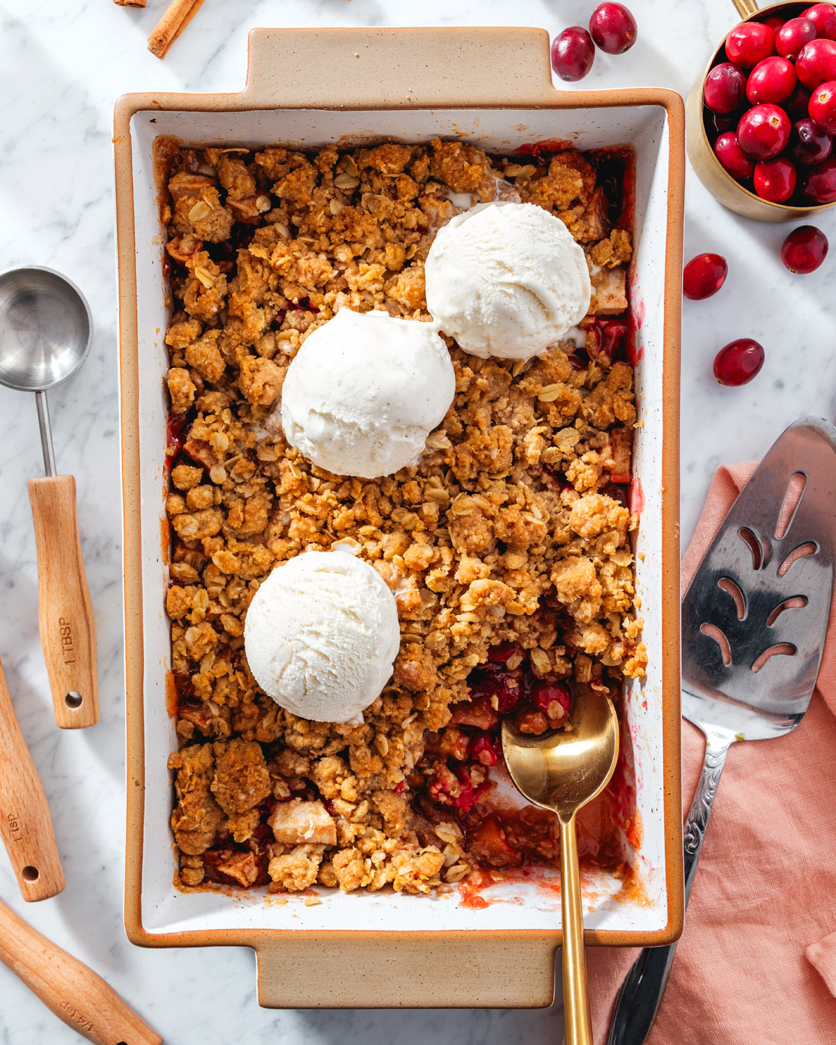 Apple Cranberry Crisp in pan with ice cream topping