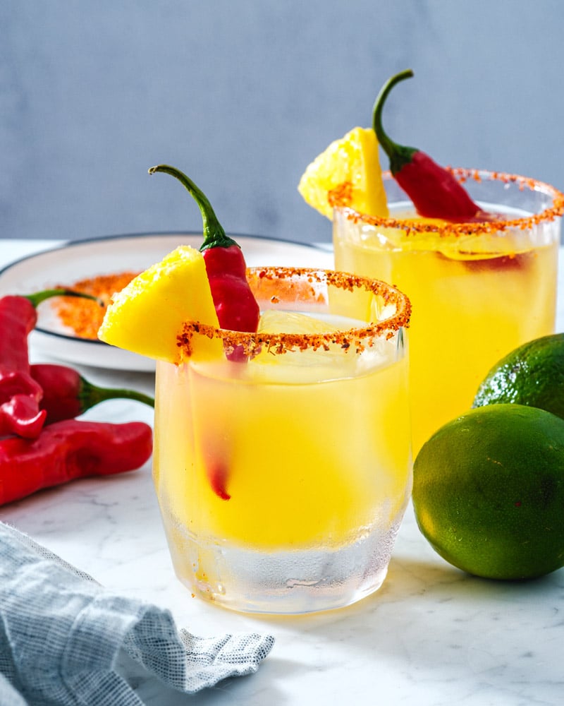 Spicy Pineapple Margarita in glass with limes and red pepper and pineapple garnish