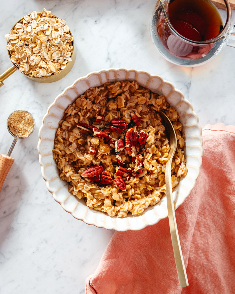 Maple Brown Sugar Oatmeal in bowl with spoon and oats in a measuring cup