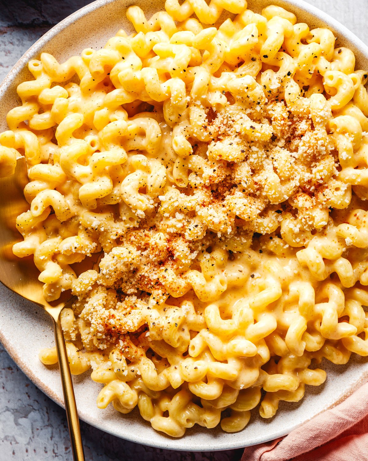 Cottage Cheese Mac and Cheese o9n a bowl with spoon and garnished with breadcrumbs.
