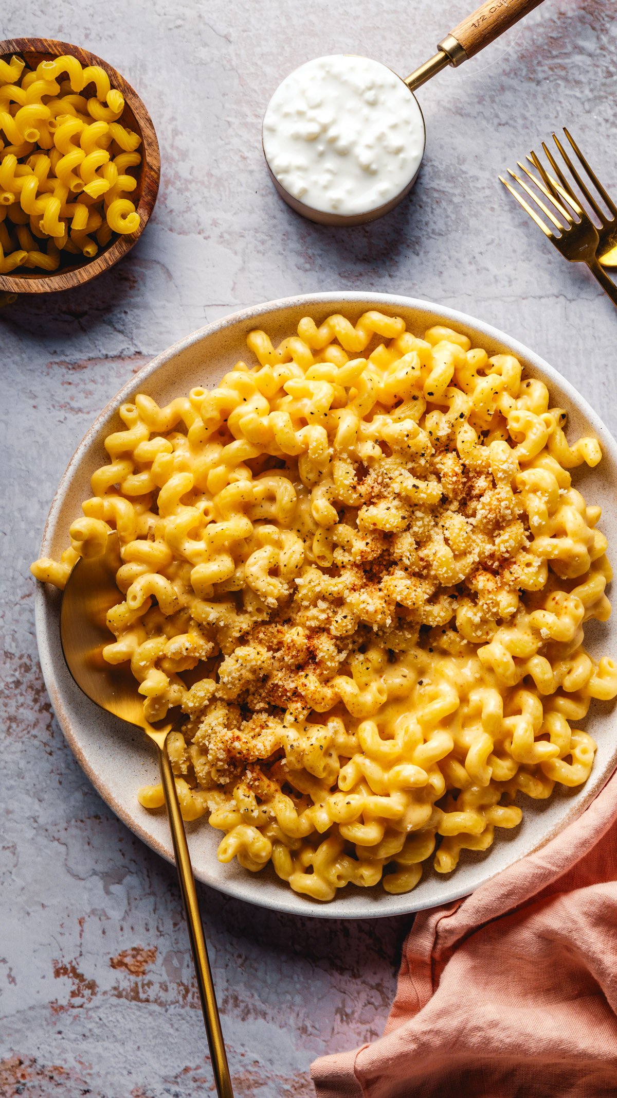 Cottage Cheese Mac and Cheese with cup of cottage cheese and noodles in background. 