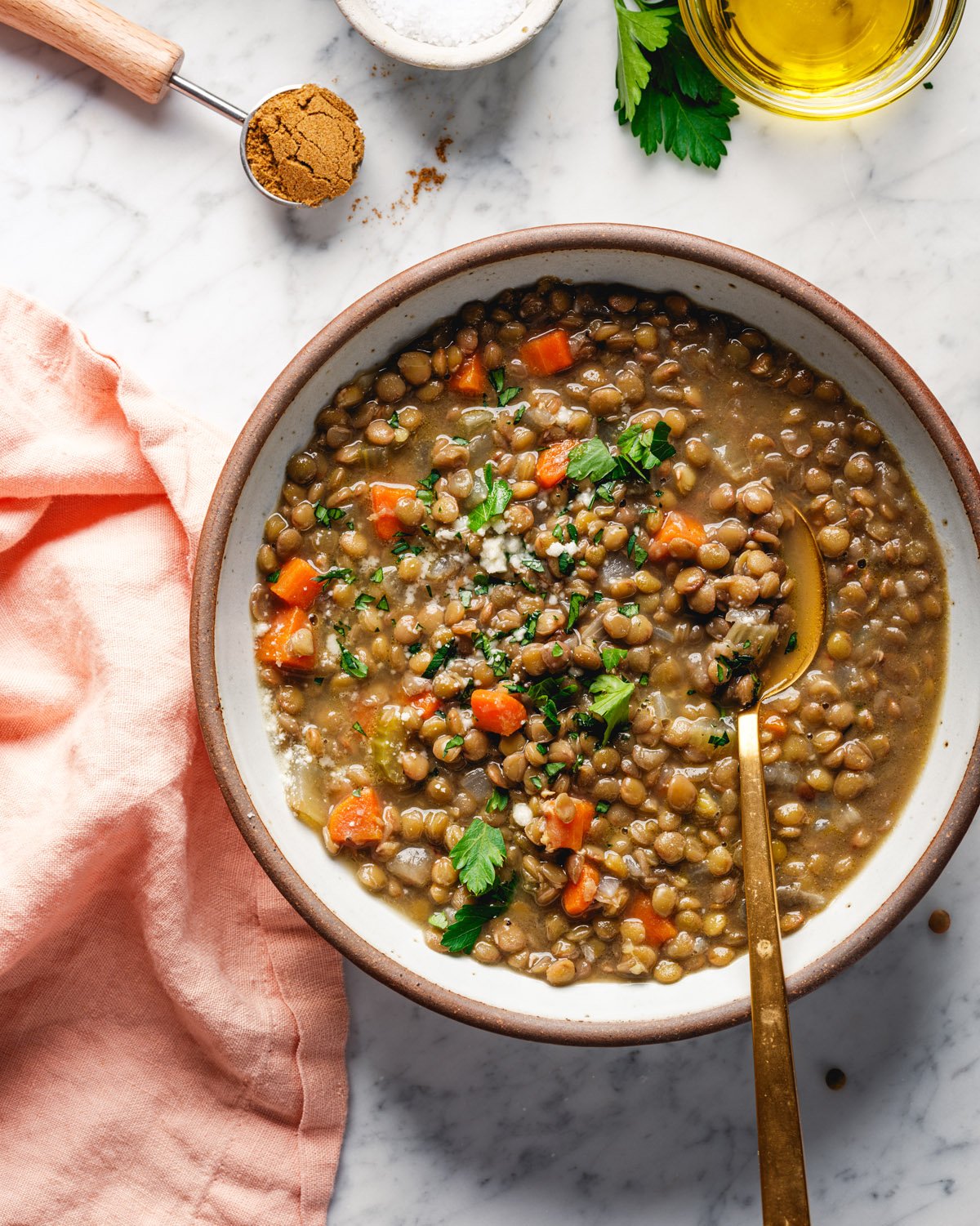 Lentil recipe: soup in bowl with spoon and garnished with parsley.