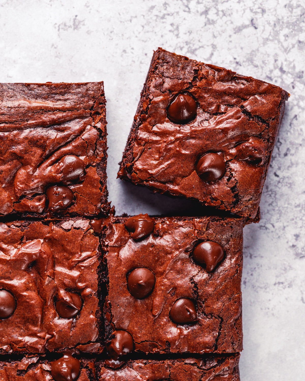 Photo of fudgy olive oil brownies with shiny tops and chocolate chips.