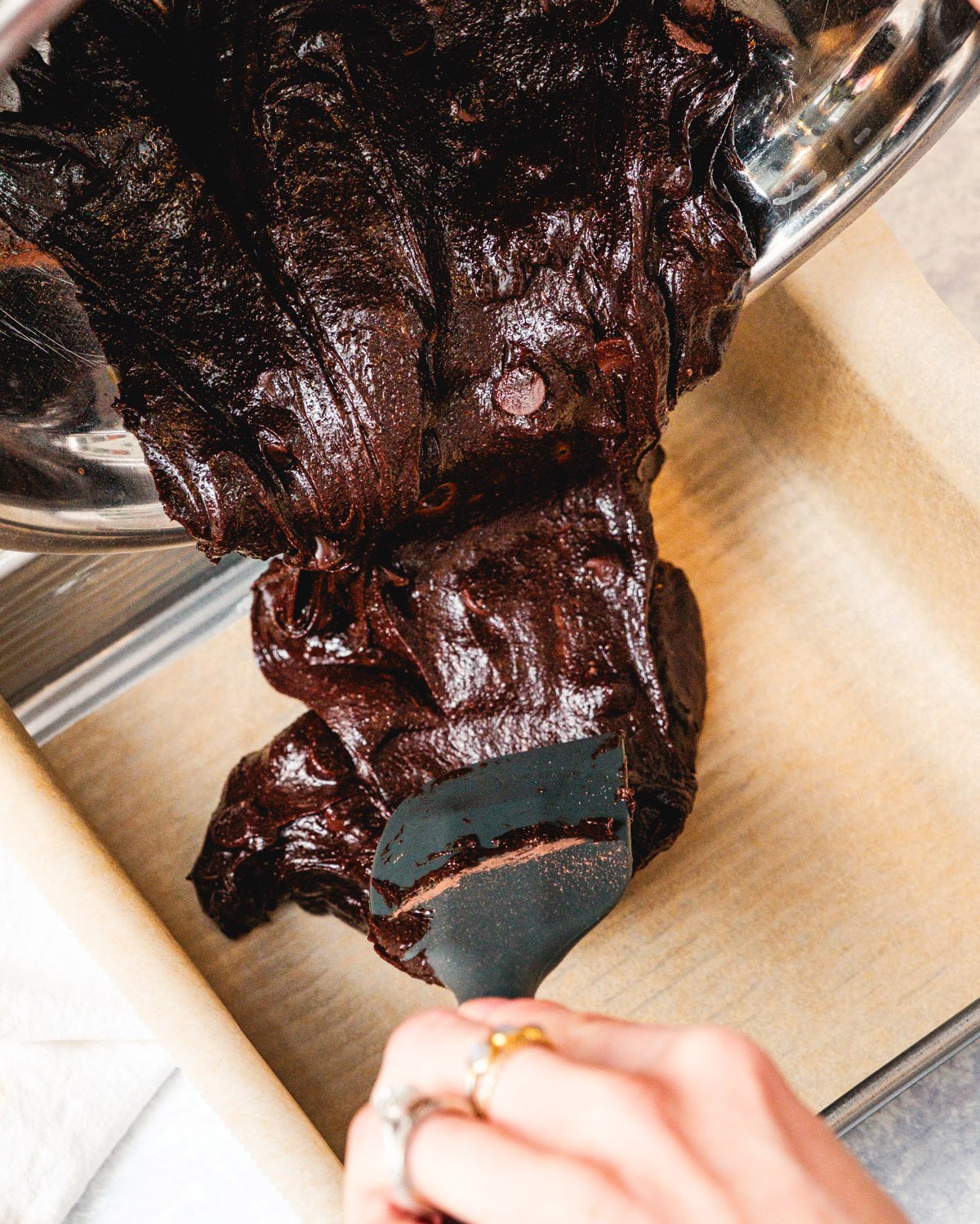 Pouring brownie batter into a prepared pan.
