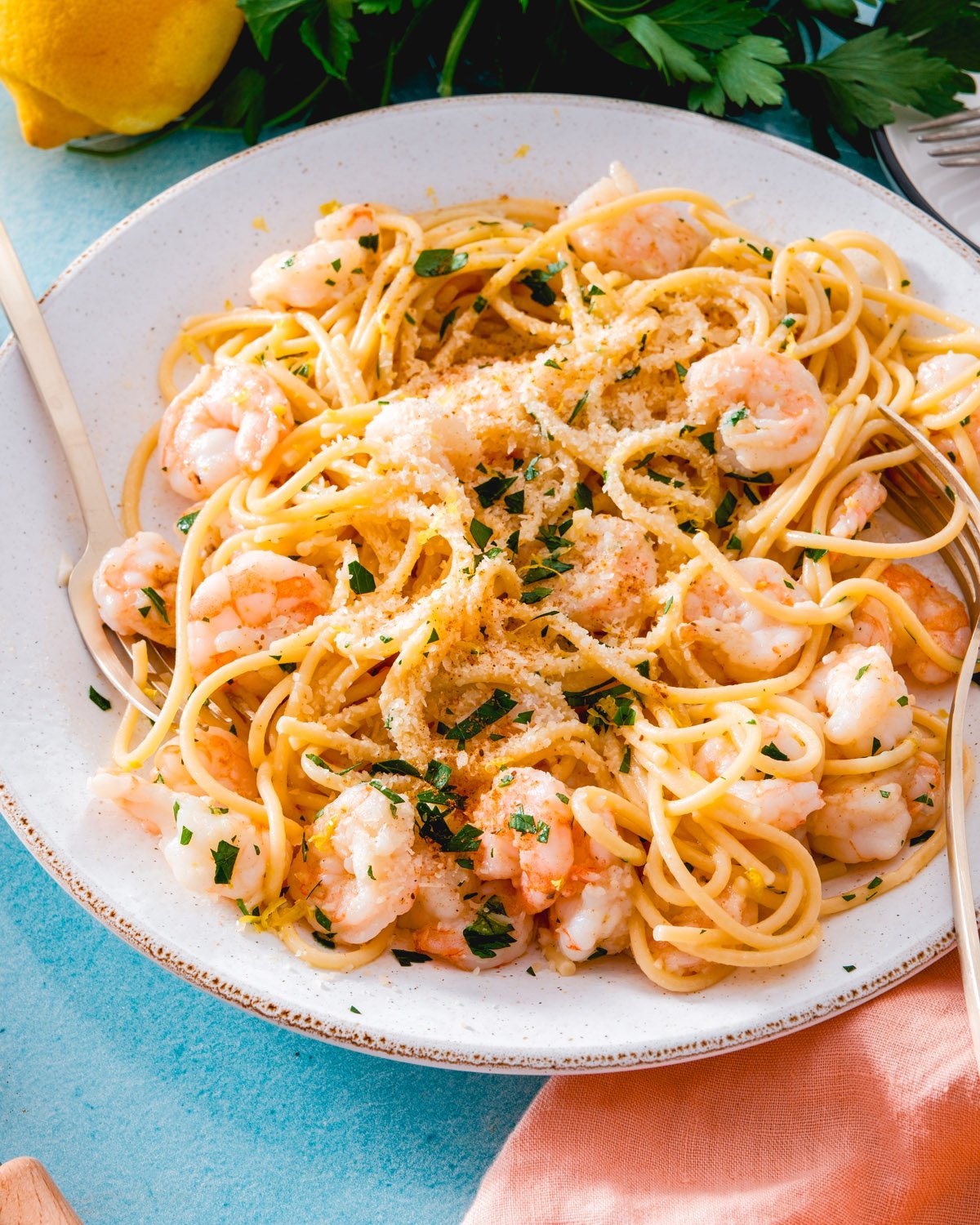 Garlic shrimp pasta on plate with Parmesan and parsley garnish.