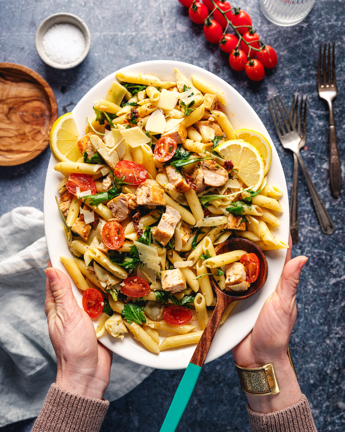 Chicken pasta salad with hands holding the platter