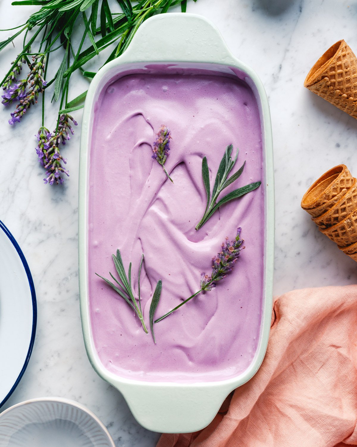Lavender ice cream in tub with fresh lavender. 