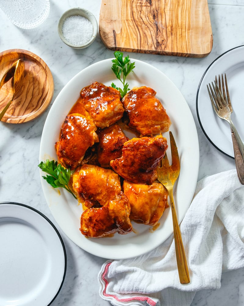 Honey Garlic Chicken Thighs on a platter with serving fork placed on marble surface