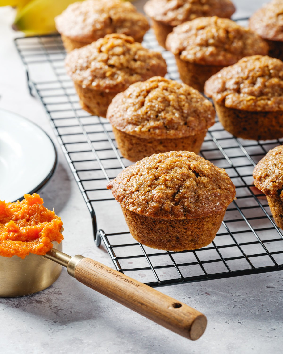 Pumpkin Banana Muffins with pumpkin puree in measuring cup