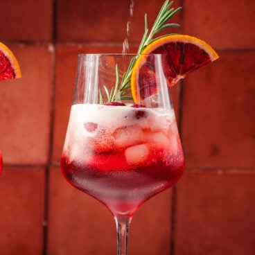 Cranberry Aperol Spritz with cranberries and rosemary garnish